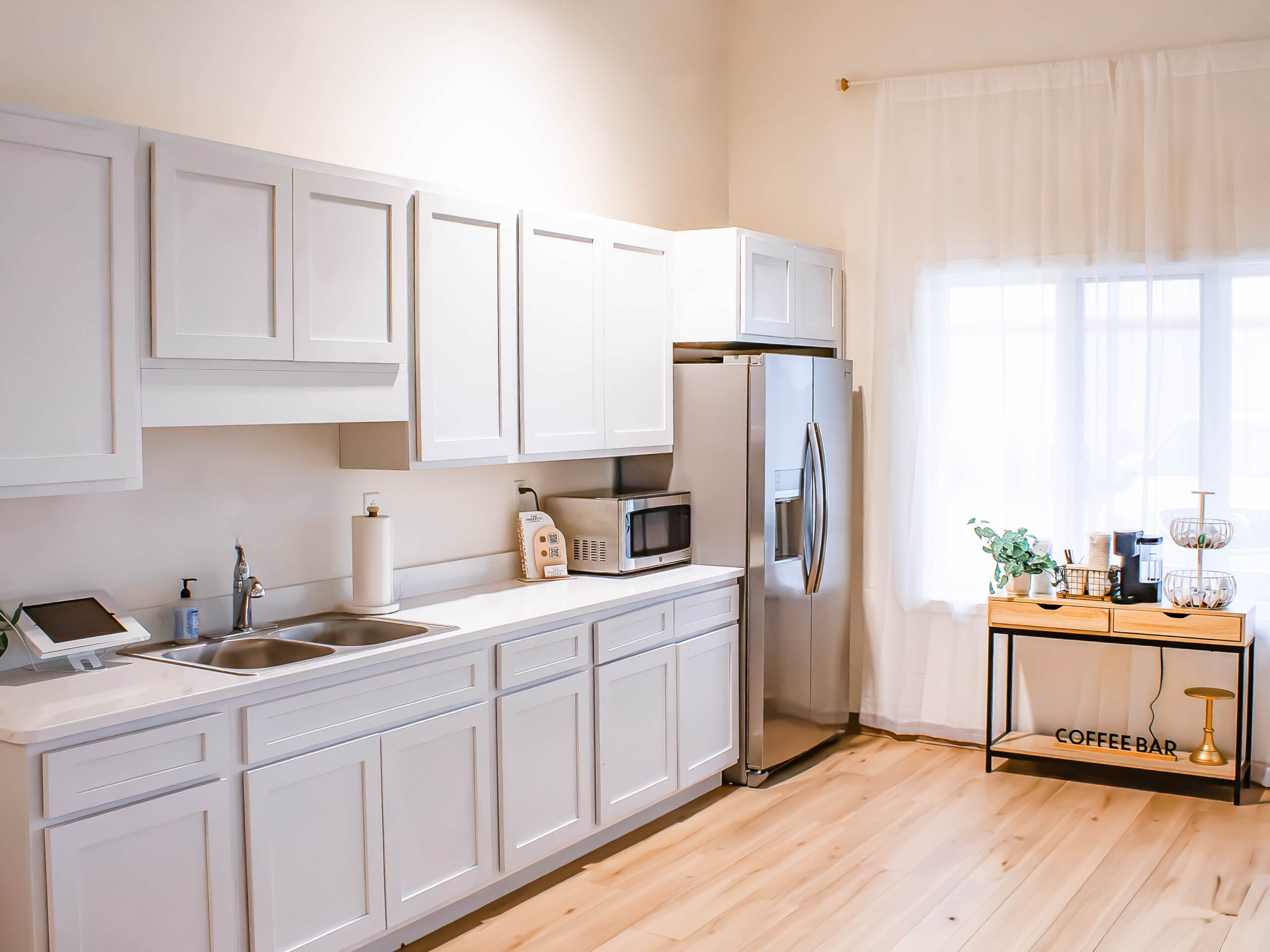 Kitchenette with white cabinets, refrigerator and prep area at The Confetti Corner venue